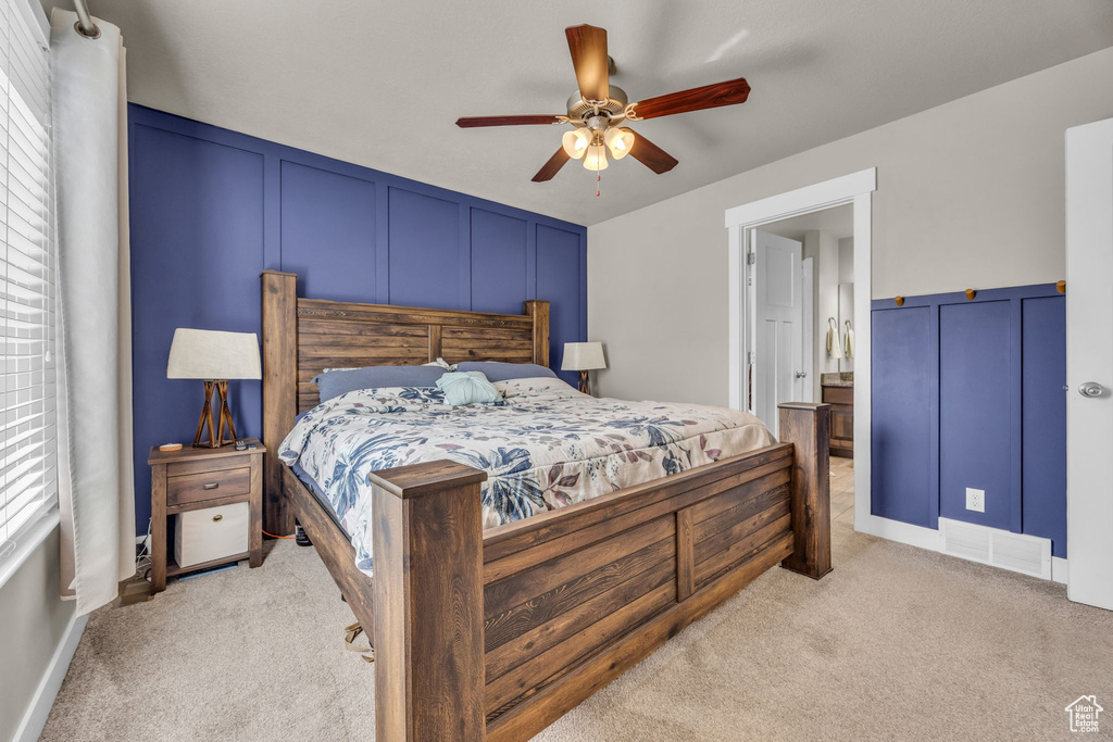Bedroom featuring light colored carpet, a decorative wall, and a ceiling fan