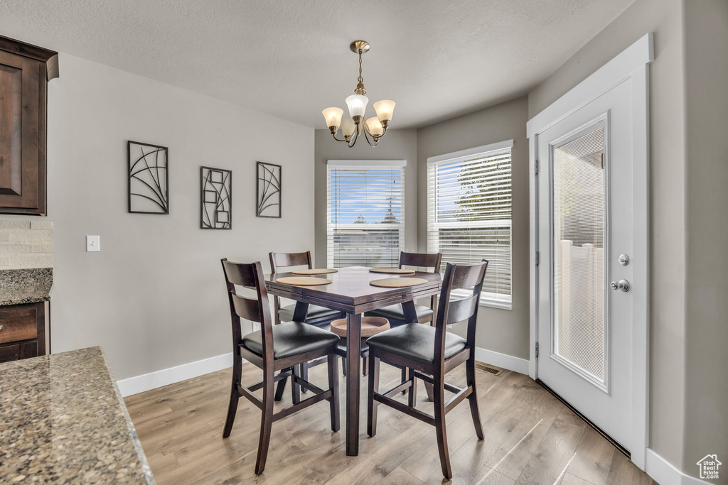 Dining room with a chandelier, light wood finished floors, and baseboards