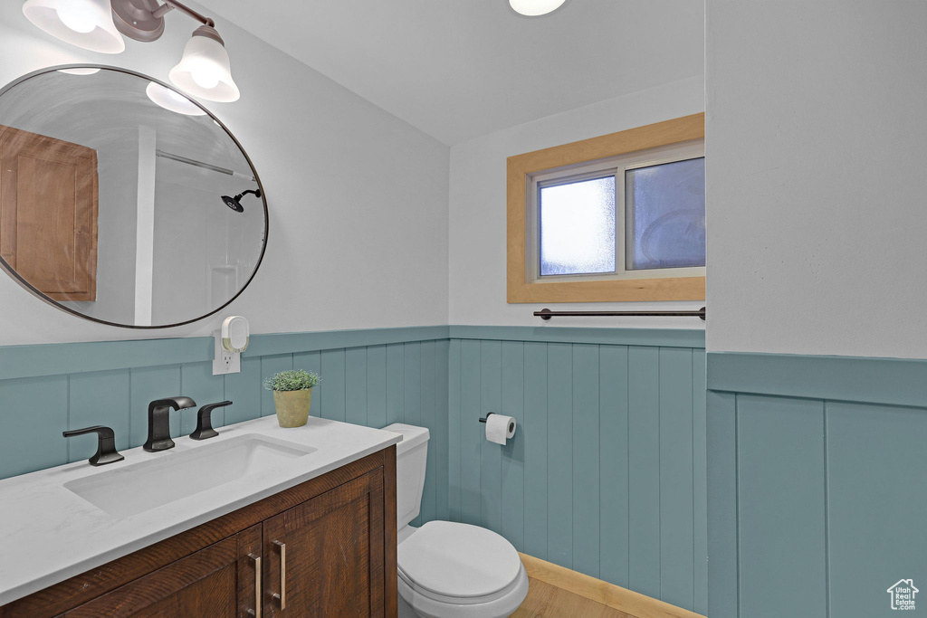 Bathroom featuring toilet, vanity, a wainscoted wall, and wood finished floors