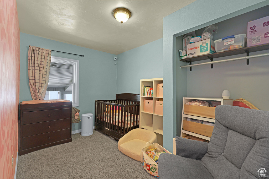 Bedroom featuring carpet and a crib