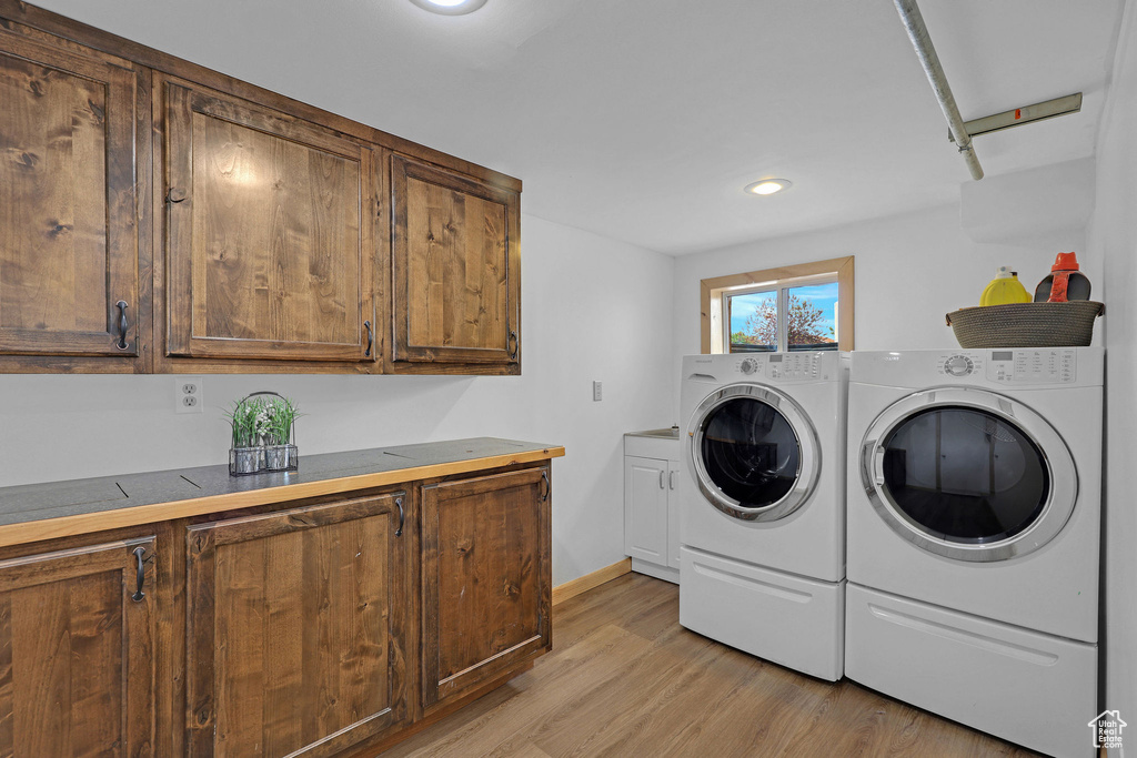 Washroom featuring cabinet space, washer and dryer, light wood finished floors, recessed lighting, and baseboards