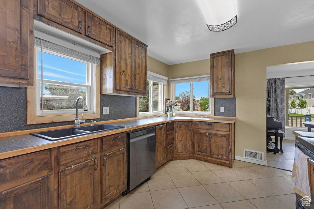 Kitchen featuring dishwashing machine, a sink, backsplash, and light tile patterned floors