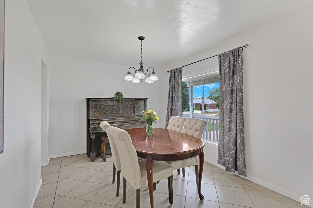 Dining area with a chandelier, light tile patterned floors, and baseboards