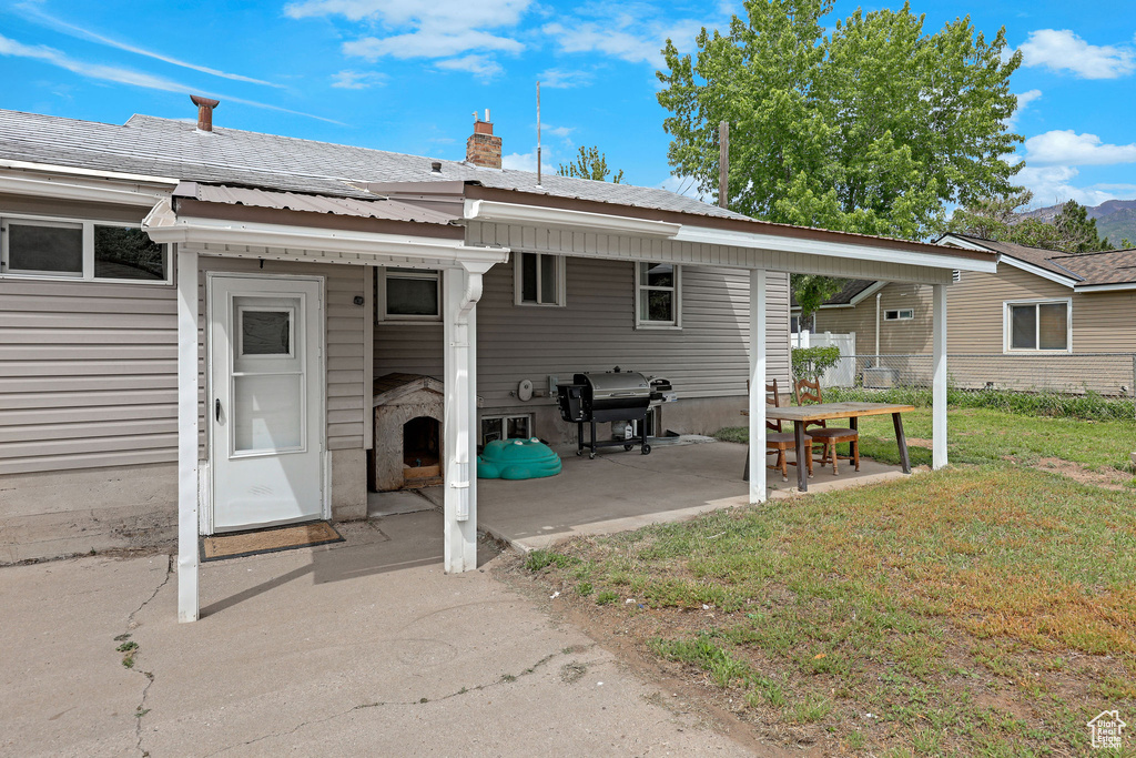 Rear view of house with a lawn, metal roof, a chimney, and a patio