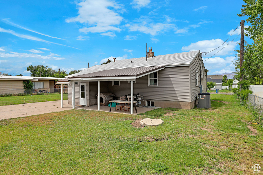 Rear view of house featuring a patio, central AC unit, and a chimney