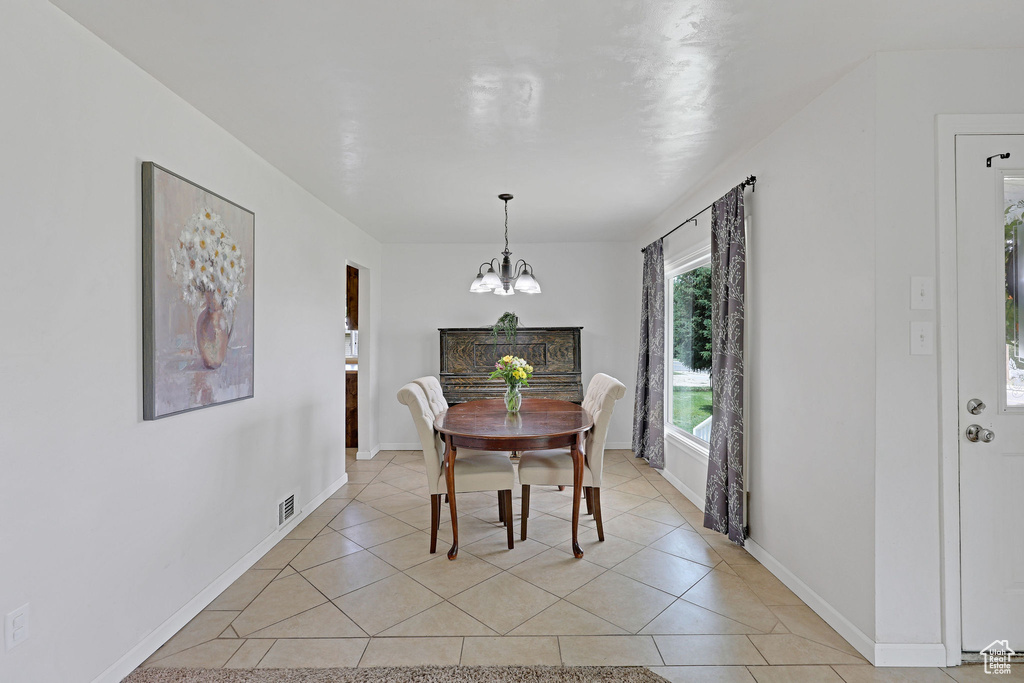 Dining area featuring a chandelier, light tile patterned floors, and baseboards