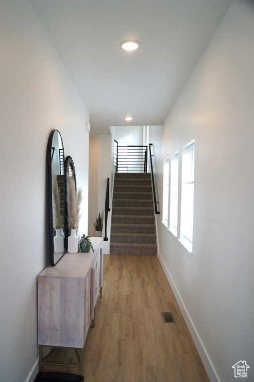Corridor featuring stairway, baseboards, light wood-style floors, and recessed lighting