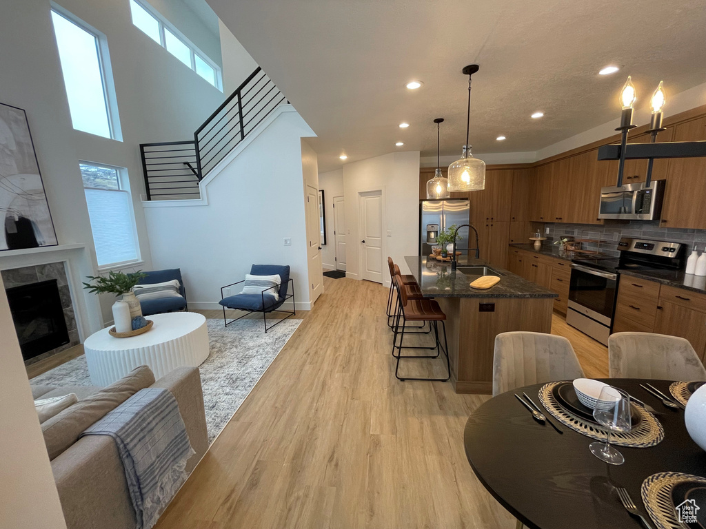 Kitchen with appliances with stainless steel finishes, brown cabinetry, a kitchen bar, a sink, and tasteful backsplash