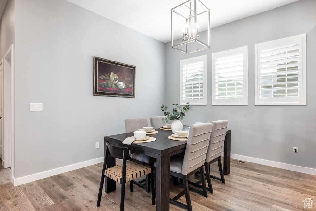 Dining space with light wood-style flooring, a chandelier, and baseboards