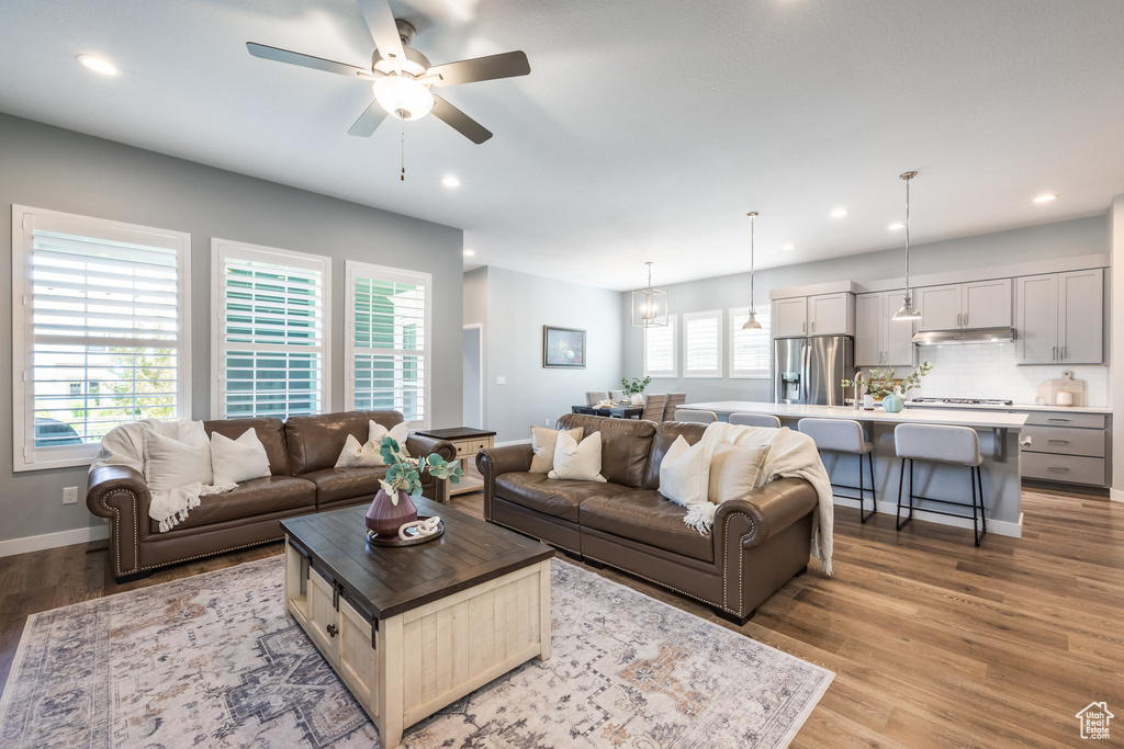 Living room featuring light wood finished floors, a ceiling fan, recessed lighting, and baseboards