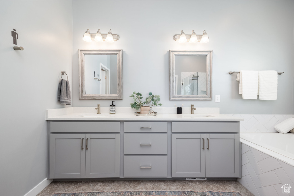 Bathroom featuring double vanity and a relaxing tiled tub