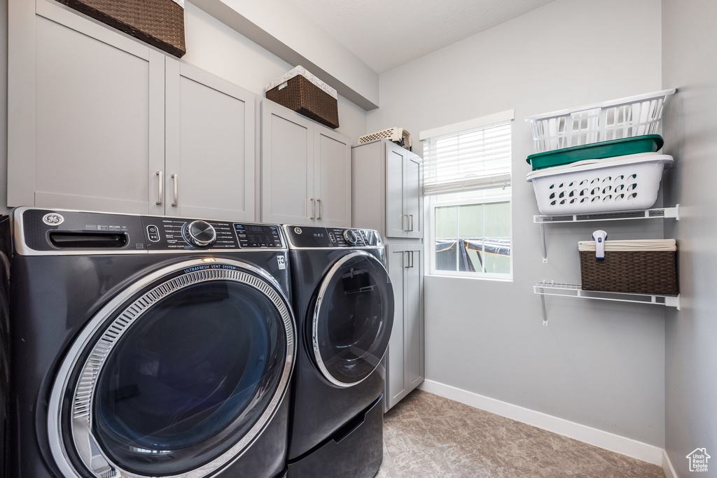 Laundry room with washing machine and clothes dryer, cabinet space, and baseboards