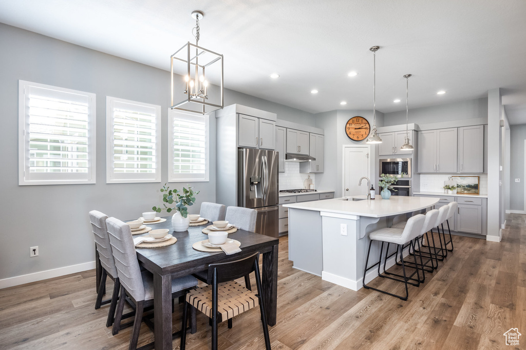 Dining space with baseboards, recessed lighting, light wood-style floors, and a chandelier