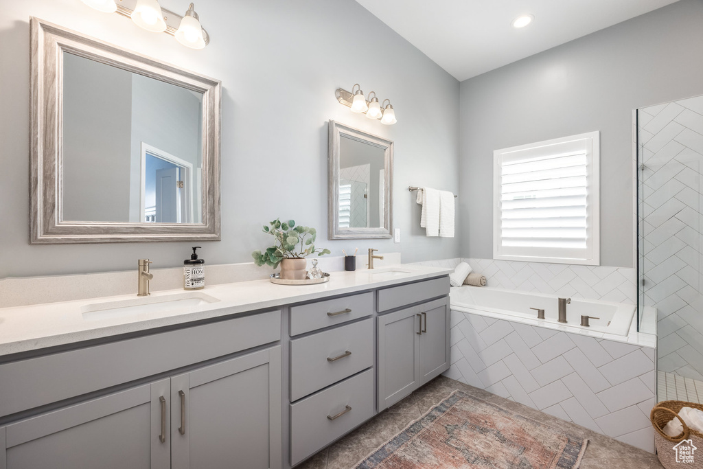 Full bathroom with double vanity, a garden tub, tile patterned flooring, and recessed lighting