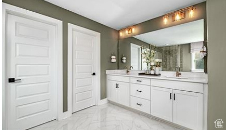 Full bath with marble look tiles, double vanity, healthy amount of natural light, and baseboards