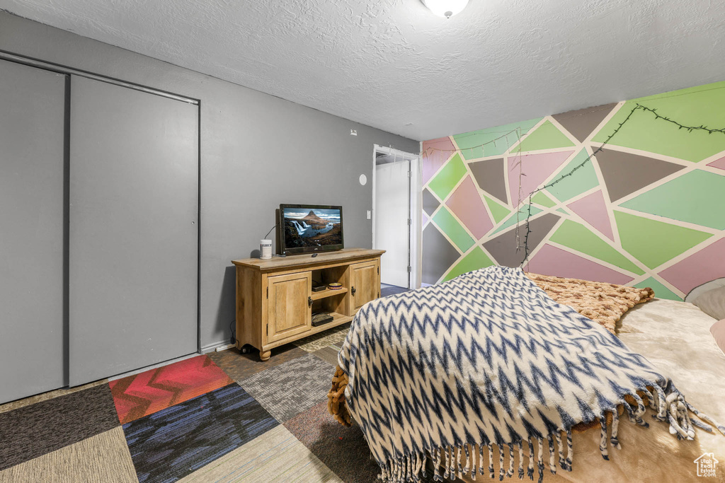 Bedroom with a textured ceiling, carpet flooring, and a closet