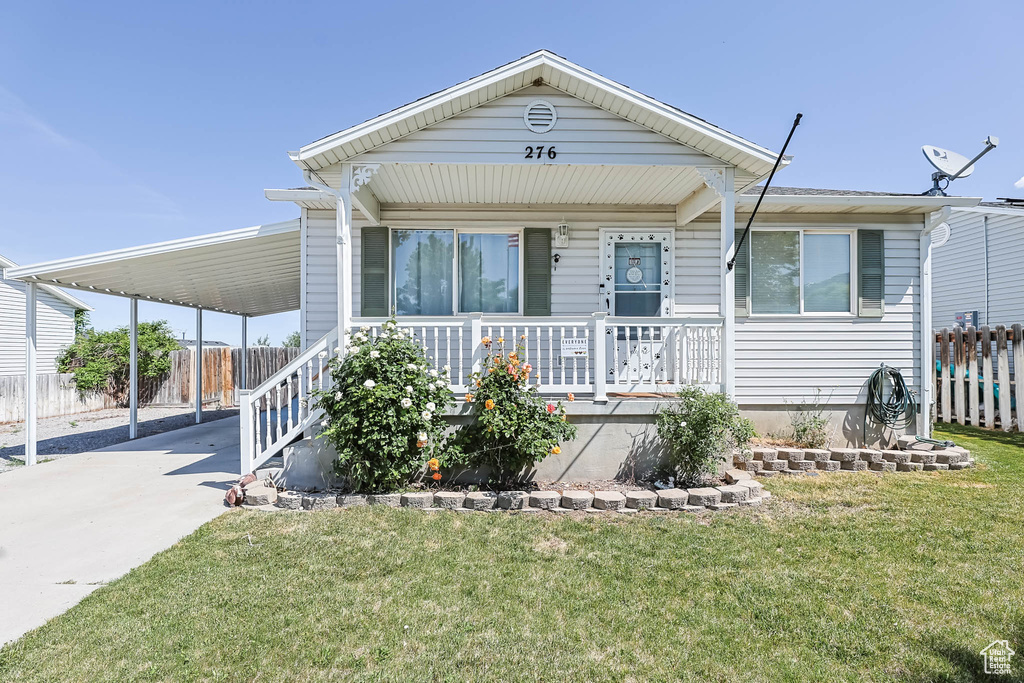 View of front facade featuring covered porch, driveway, and a carport