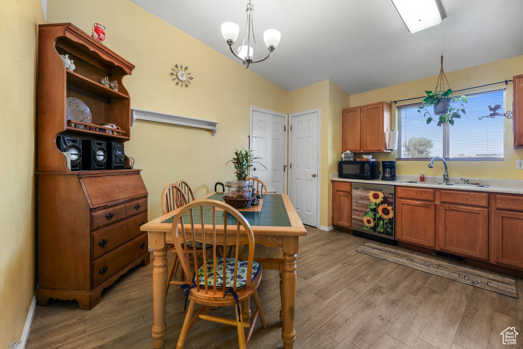 Kitchen with dishwasher, a sink, black microwave, and light wood-type flooring