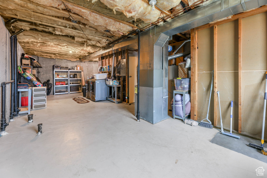 Unfinished below grade area featuring washer / clothes dryer and heating unit
