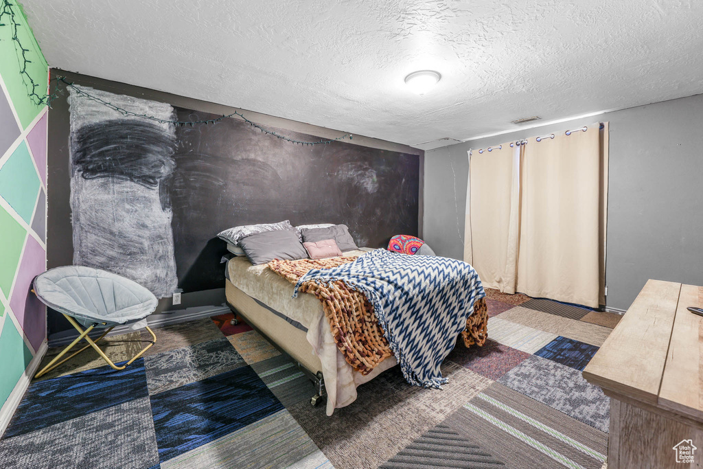 Bedroom with a textured ceiling and baseboards