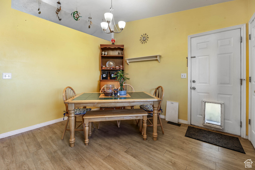 Dining space featuring light wood-style flooring, a chandelier, and baseboards