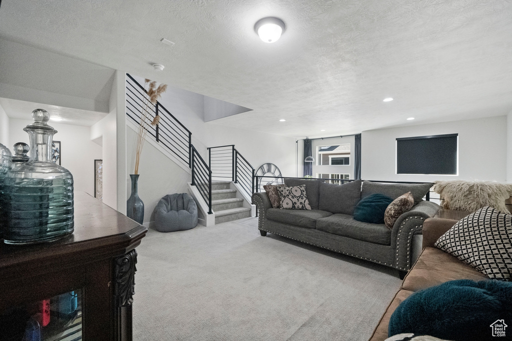 Carpeted living room with stairway, a textured ceiling, and recessed lighting