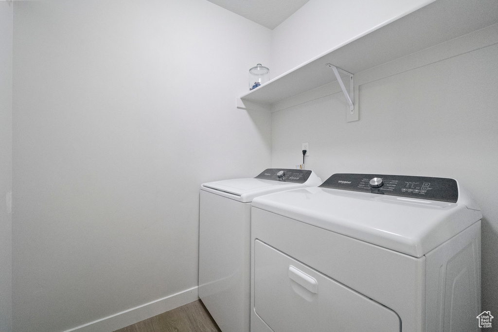Washroom featuring independent washer and dryer, wood finished floors, and baseboards