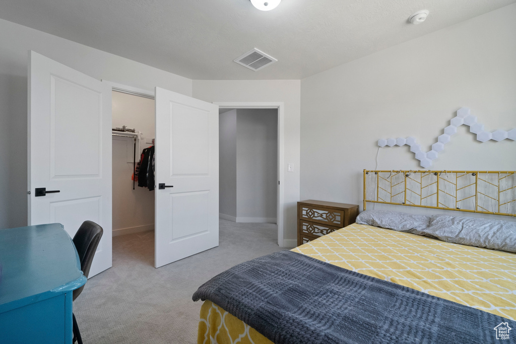 Carpeted bedroom featuring a walk in closet, a closet, and baseboards
