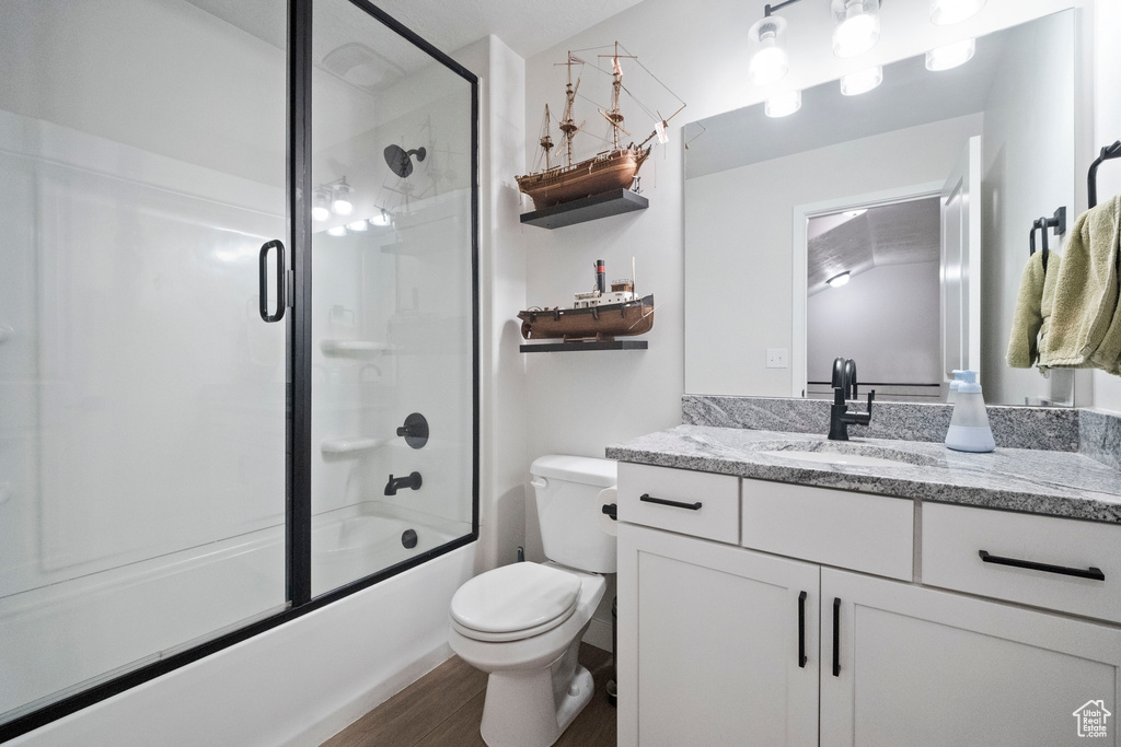 Full bathroom featuring vanity, toilet, shower / bath combination with glass door, and wood finished floors