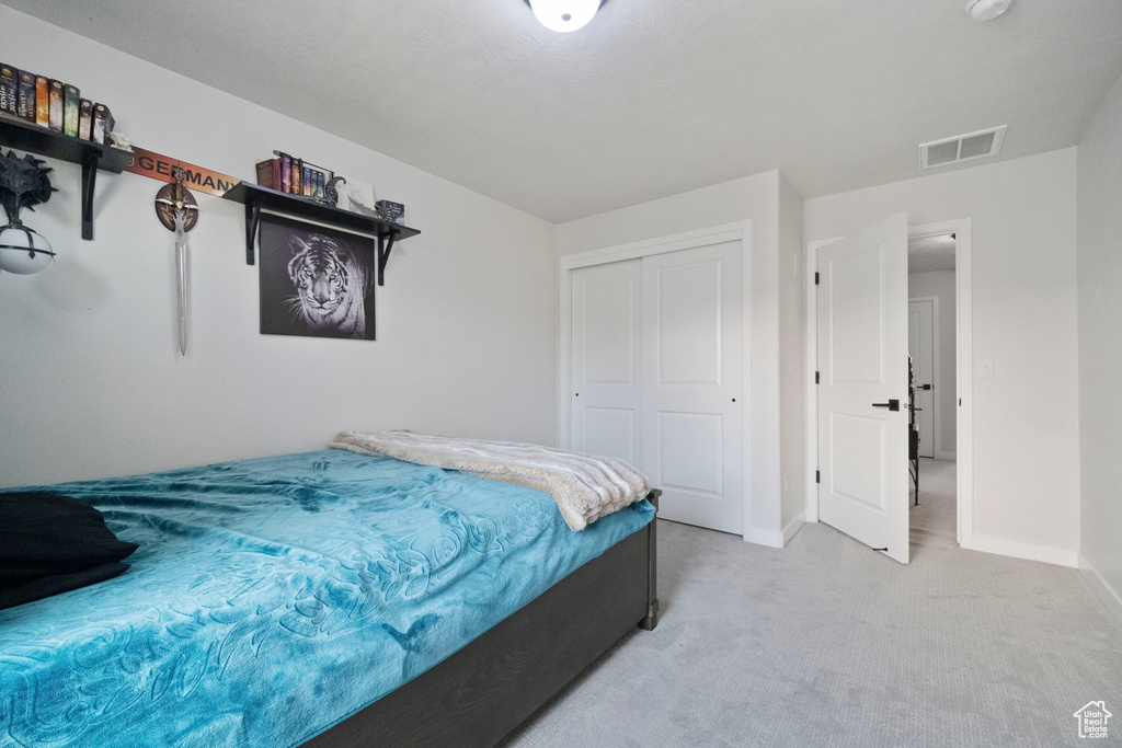 Bedroom featuring a closet, baseboards, and light carpet