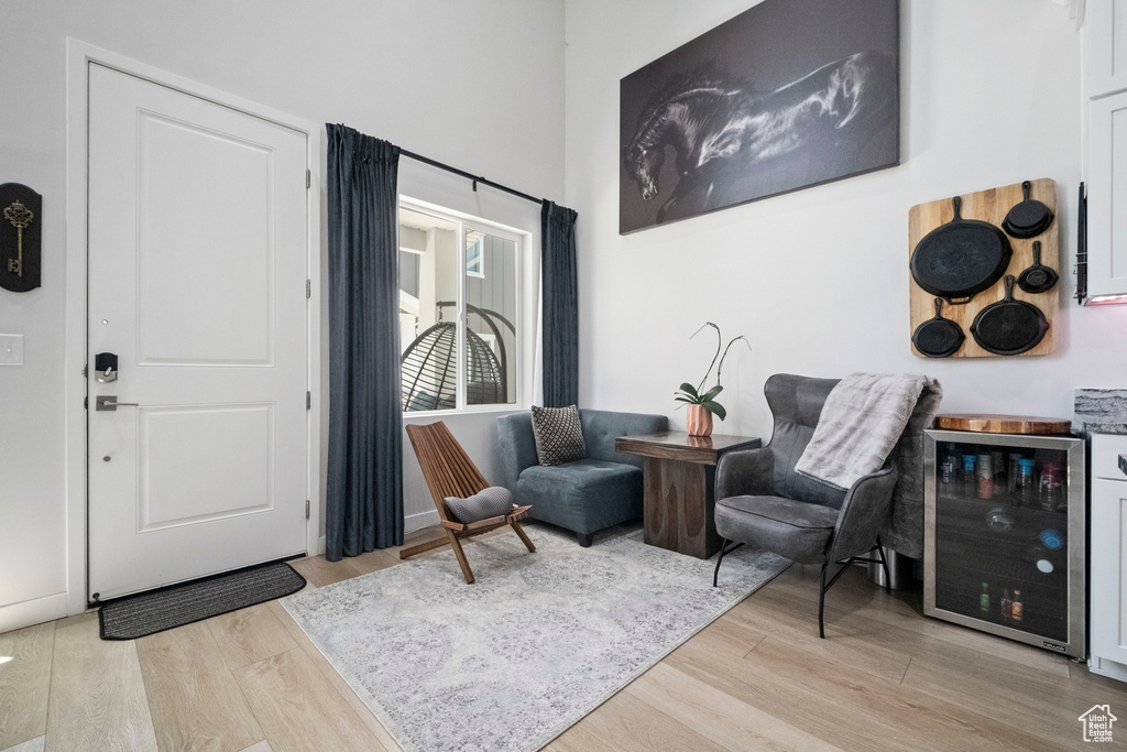 Sitting room with light wood-style floors, beverage cooler, and a towering ceiling