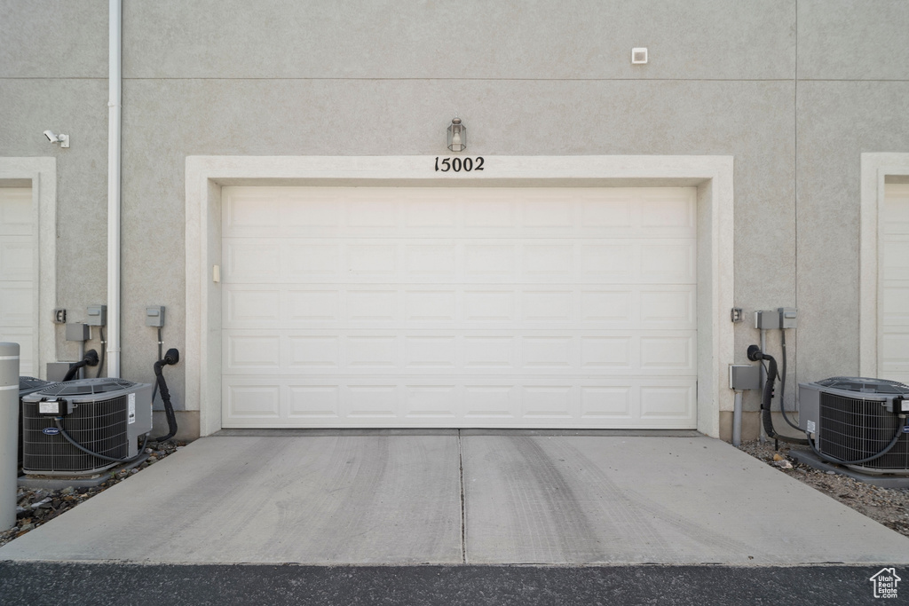 Garage featuring central AC unit and concrete driveway