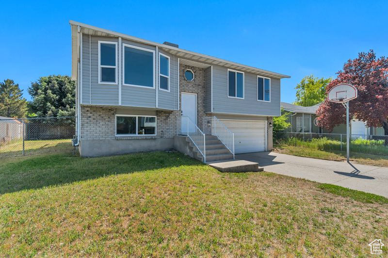 Split foyer home with concrete driveway, brick siding, and a garage