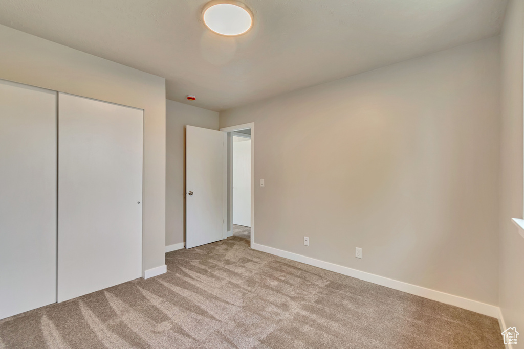 Unfurnished bedroom featuring carpet, baseboards, and a closet