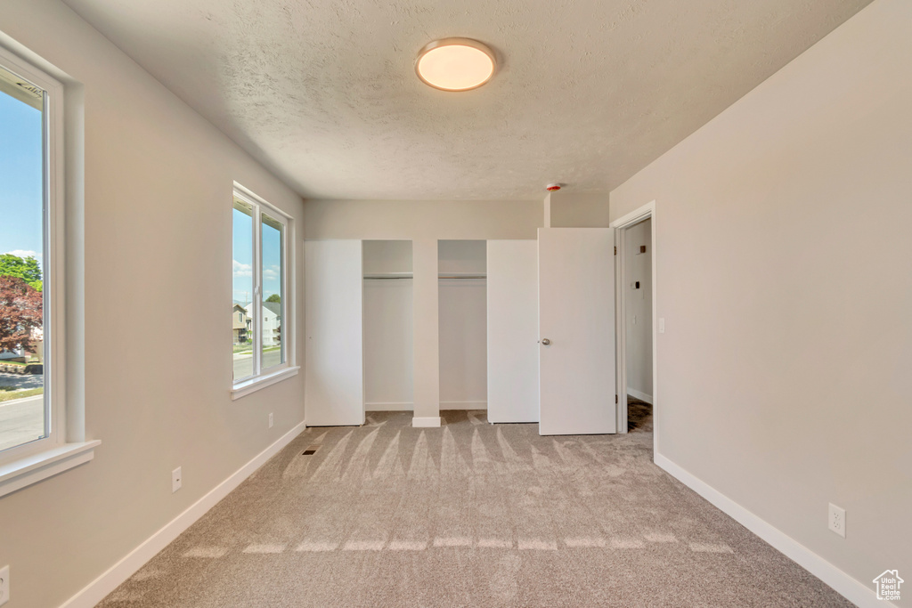 Unfurnished bedroom featuring carpet flooring, a textured ceiling, and baseboards