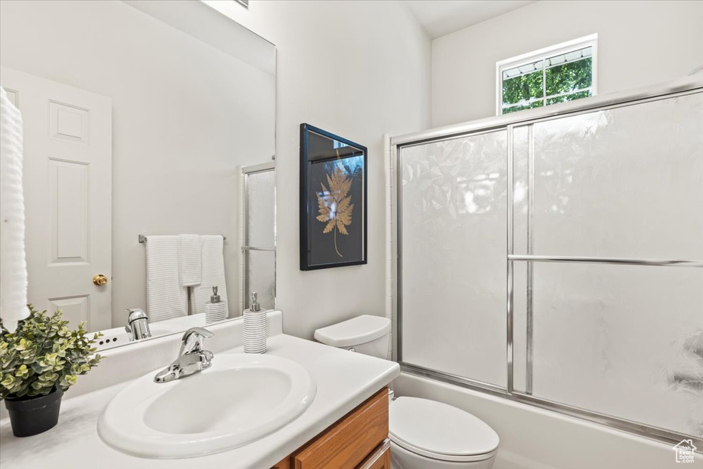 Bathroom with vanity, toilet, and enclosed tub / shower combo