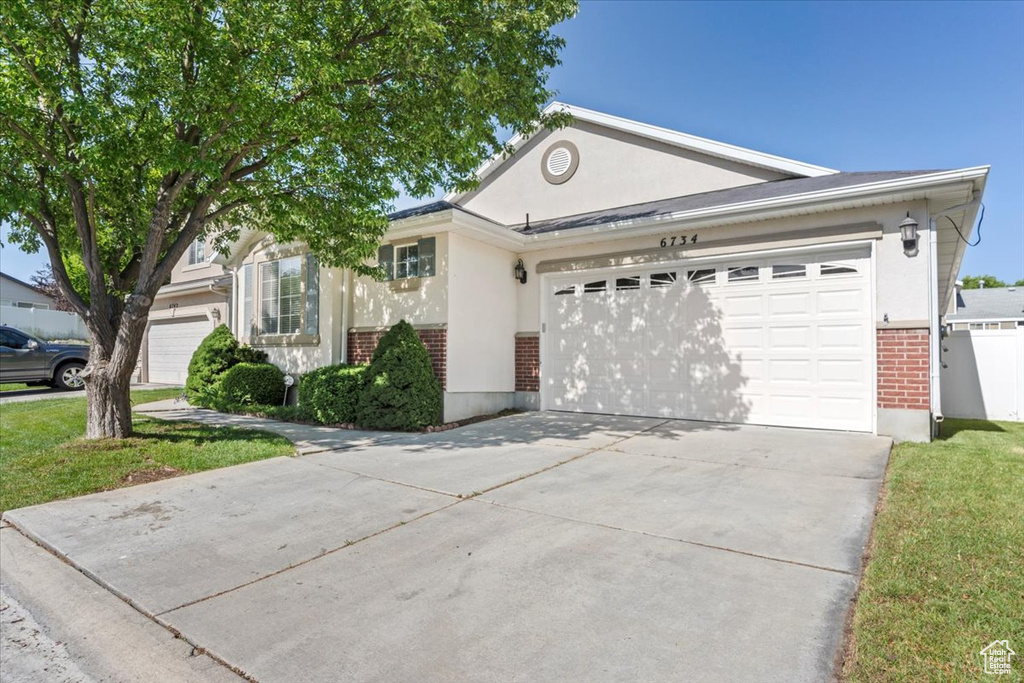 Ranch-style home with brick siding, an attached garage, concrete driveway, and stucco siding