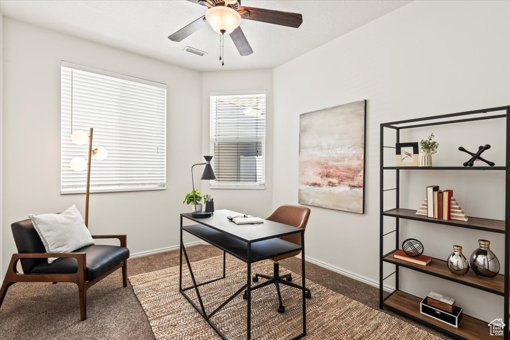 Carpeted office featuring a ceiling fan and baseboards