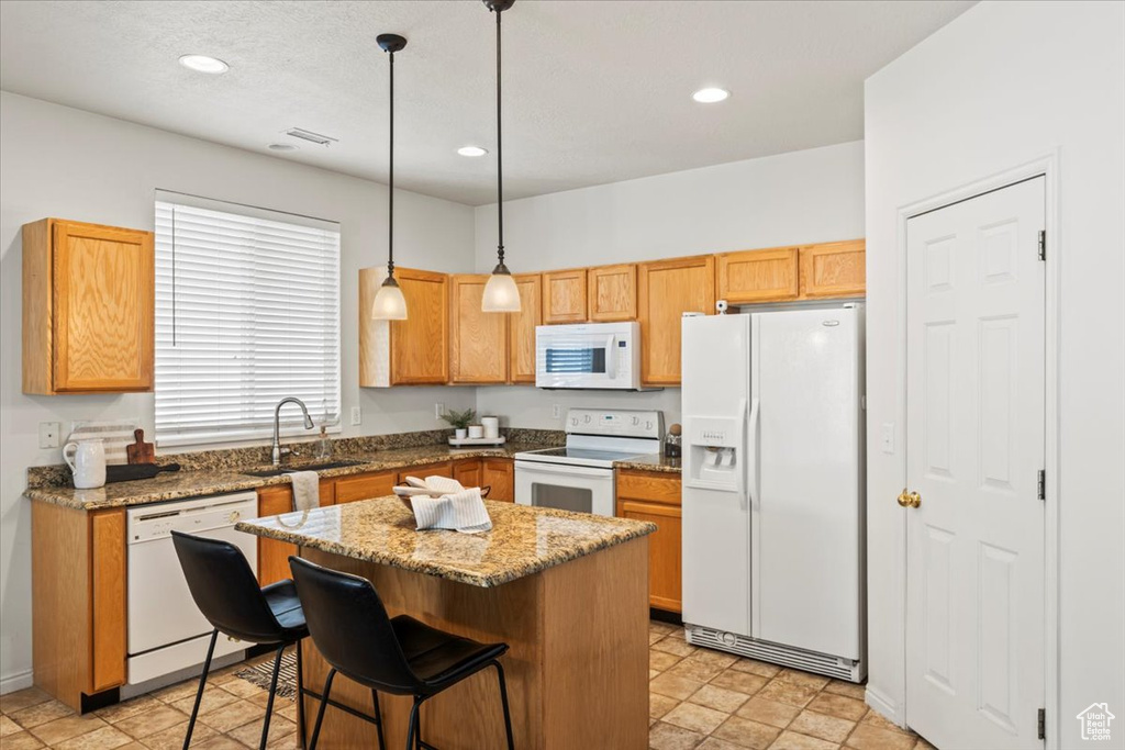 Kitchen featuring white appliances, a sink, a kitchen island, pendant lighting, and recessed lighting