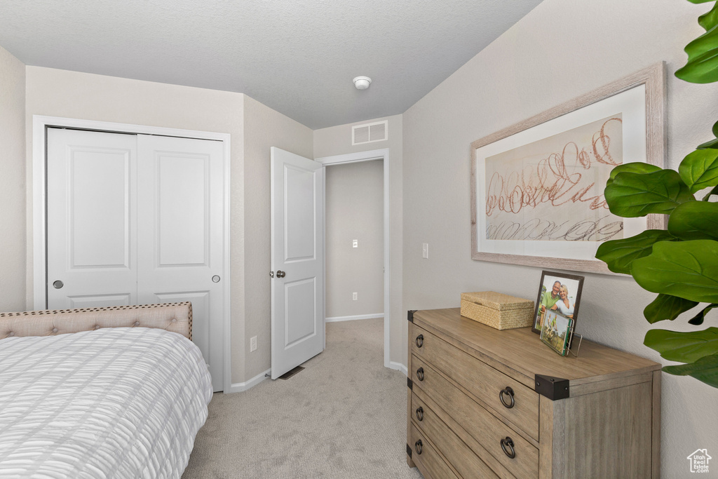 Bedroom with light colored carpet, baseboards, and a closet