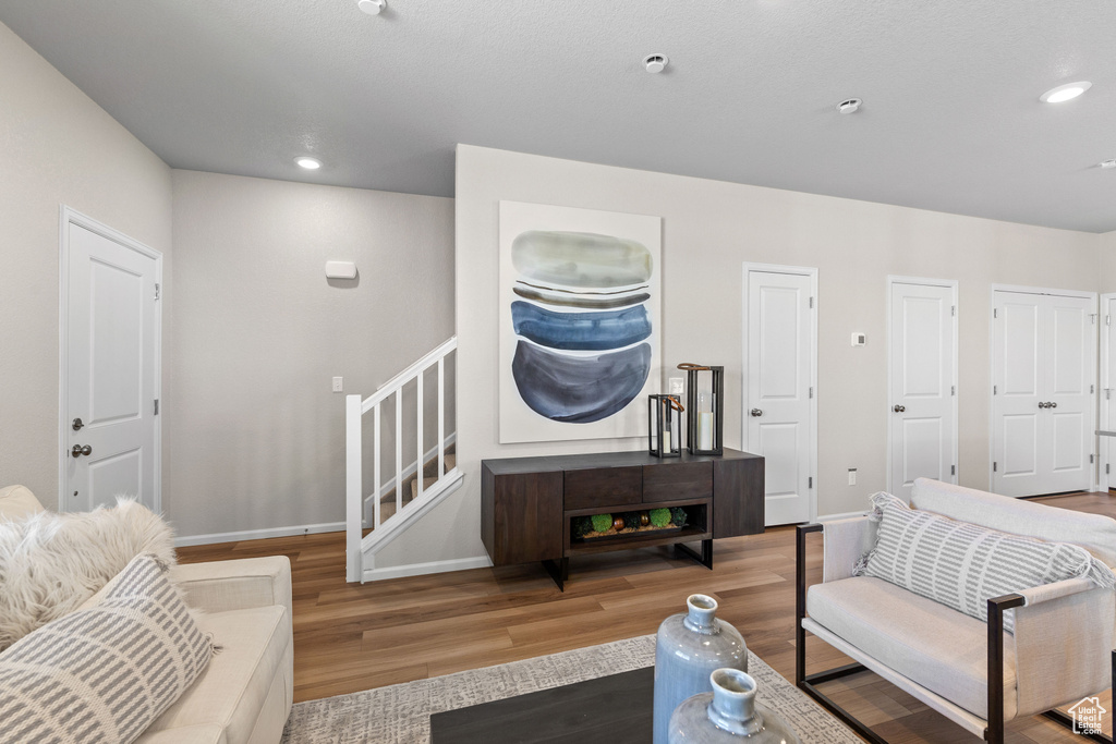 Living area with wood finished floors, baseboards, stairs, and recessed lighting