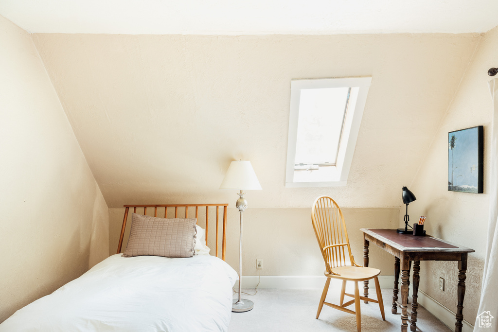Carpeted bedroom with vaulted ceiling and baseboards