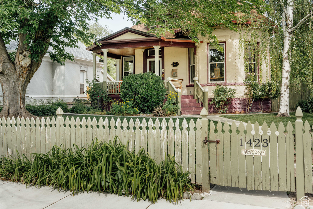 View of front of property with covered porch, a fenced front yard, and brick siding