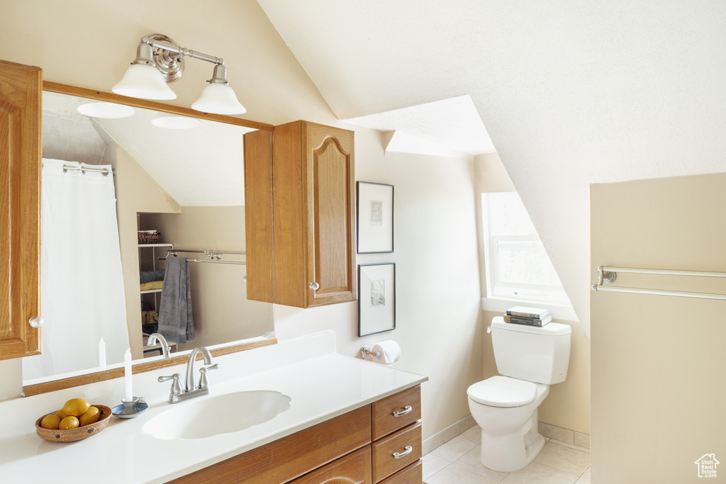 Bathroom featuring lofted ceiling, tile patterned floors, vanity, and toilet