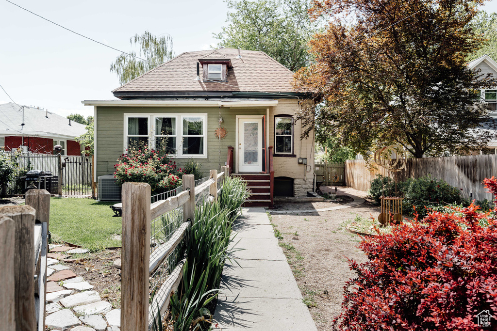 Bungalow with entry steps, a shingled roof, a fenced backyard, and central AC unit