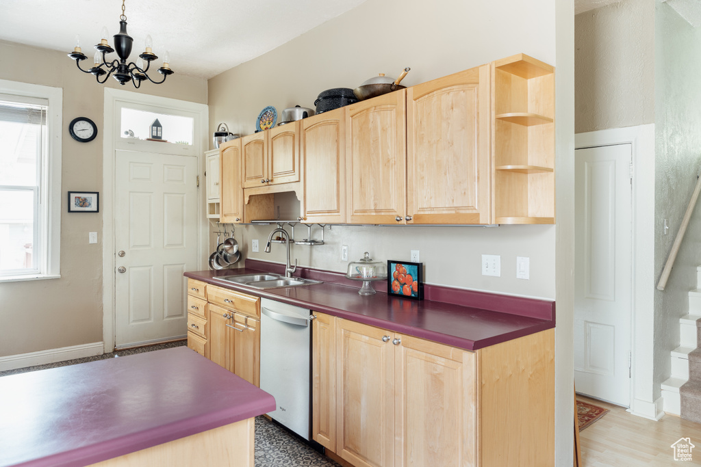 Kitchen with a sink, light brown cabinets, dark countertops, and dishwashing machine