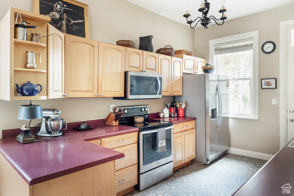 Kitchen with stainless steel appliances, light brown cabinetry, open shelves, a chandelier, and baseboards