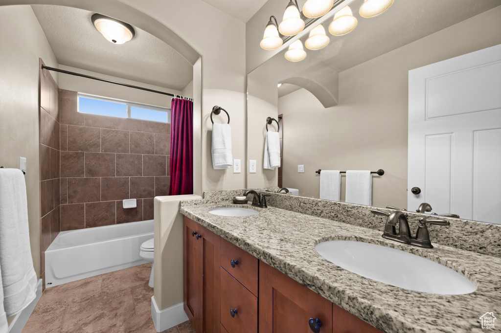 Bathroom featuring double vanity, shower / bath combo with shower curtain, and toilet