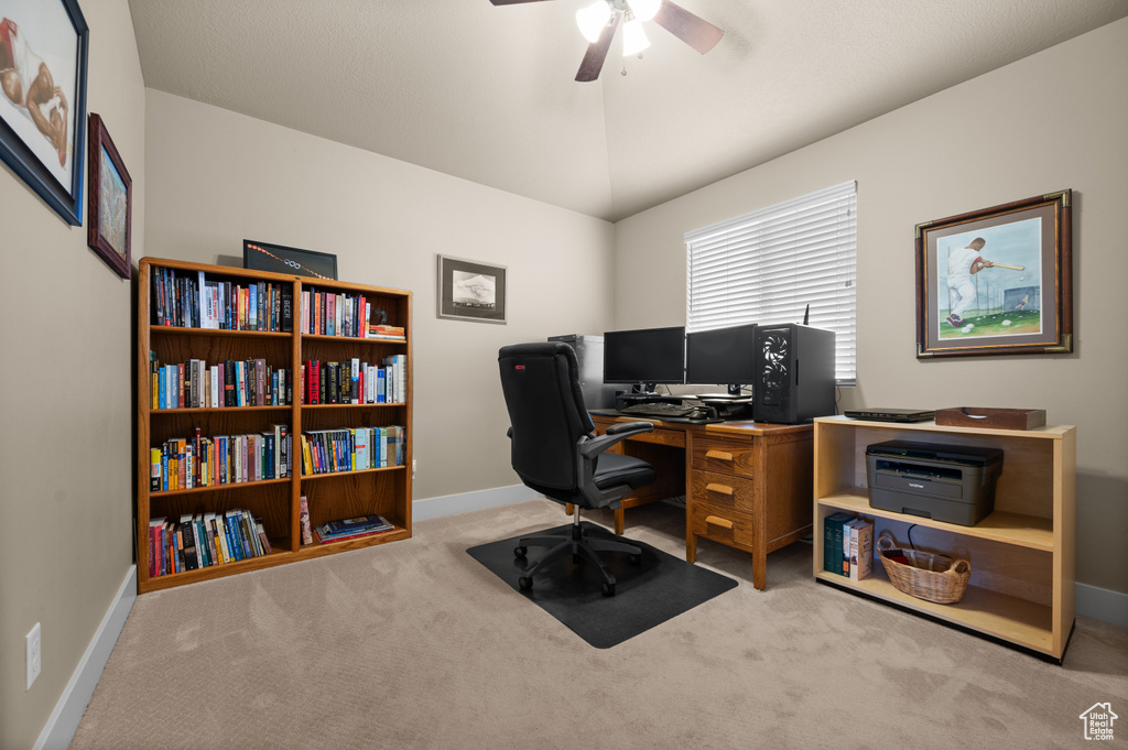 Carpeted home office featuring a ceiling fan and baseboards