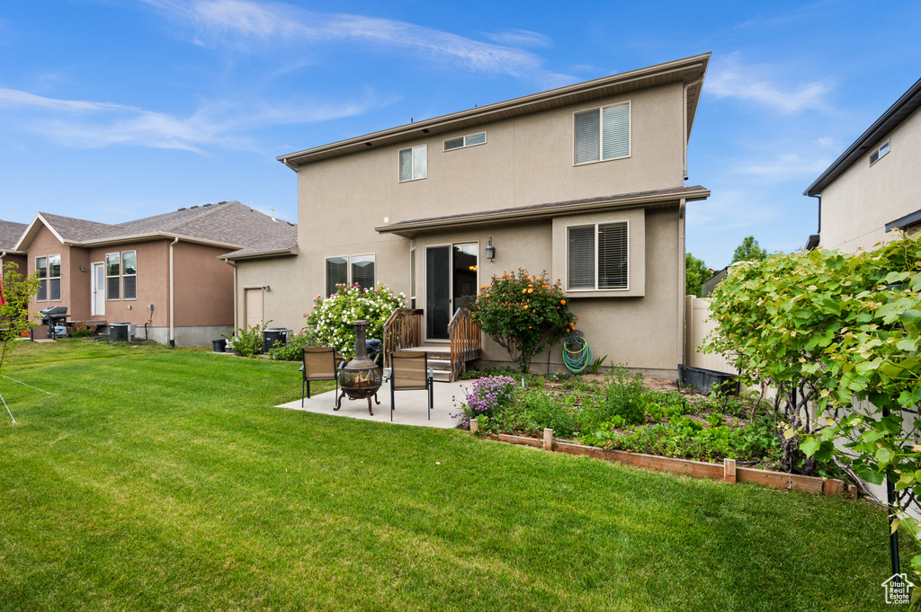 Rear view of property with a patio, stucco siding, central AC unit, and a garden